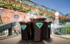 Drei Mülltonnen mit Superhelden Aufkleber vor Wuppertaler Schwebebahnbrücke